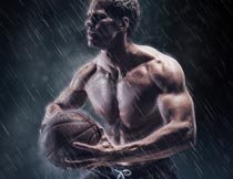 雨中抱起篮球投篮的肌肉男摄影图片